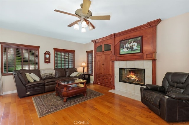 29944 Peach Tree Ct, Murrieta, CA 92563 - living area with light wood-style flooring, ceiling fan, a tiled fireplace, and baseboards