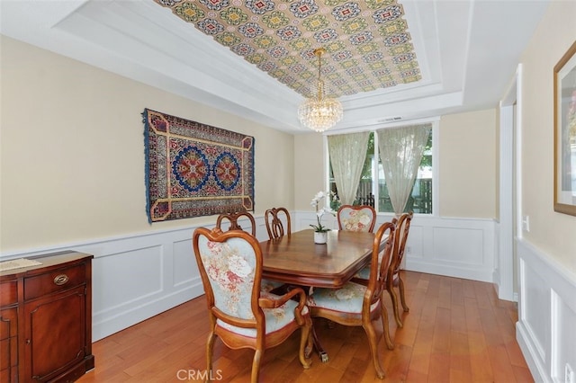 29944 Peach Tree Ct, Murrieta, CA 92563 - dining room with a raised ceiling, a chandelier, light wood finished floors, a wainscoted wall, and a decorative wall
