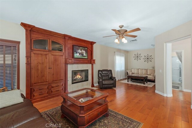 29944 Peach Tree Ct, Murrieta, CA 92563 - living area featuring a ceiling fan, light wood-style floors, a tiled fireplace, and baseboards