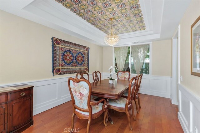29944 Peach Tree Ct, Murrieta, CA 92563 - dining room featuring a tray ceiling, a chandelier, light wood-type flooring, a decorative wall, and wainscoting