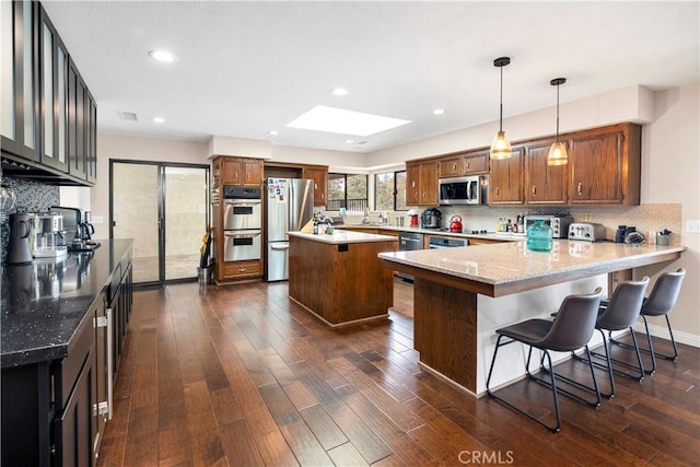 735 Del Valle Dr, Fallbrook, CA 92028 - kitchen with appliances with stainless steel finishes, a peninsula, dark wood finished floors, decorative backsplash, and a skylight