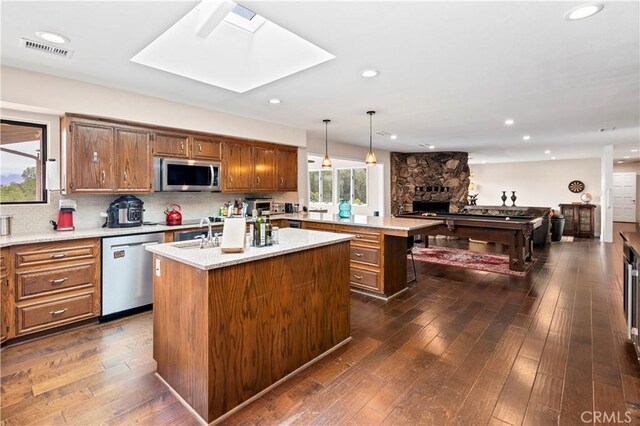 735 Del Valle Dr, Fallbrook, CA 92028 - kitchen featuring stainless steel appliances, an island with sink, a peninsula, a stone fireplace, and a sink
