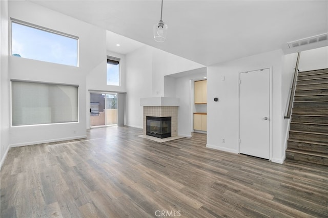 27906 Amber Unit 231, Mission Viejo, CA 92691 - unfurnished living room featuring wood finished floors, stairs, a towering ceiling, a tile fireplace, and baseboards
