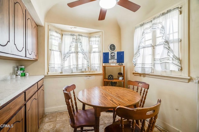 1120 S Burnside Ave, Los Angeles, CA 90019 - dining room featuring baseboards, a ceiling fan, plenty of natural light, light stone finish flooring, and vaulted ceiling