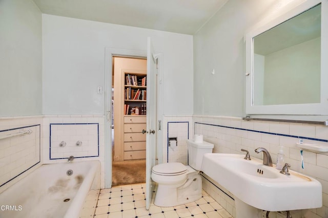 1120 S Burnside Ave, Los Angeles, CA 90019 - full bathroom featuring a garden tub, toilet, a wainscoted wall, tile walls, and a sink