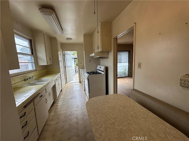 863 S Vanhorn Ave N, West Covina, CA 91790 - kitchen with white gas range oven, tile countertops, a sink, under cabinet range hood, and white cabinetry