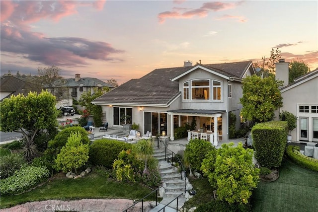 2567 Oakshore, Westlake Village, CA 91361 - back of property at dusk with a chimney, stucco siding, and a patio area