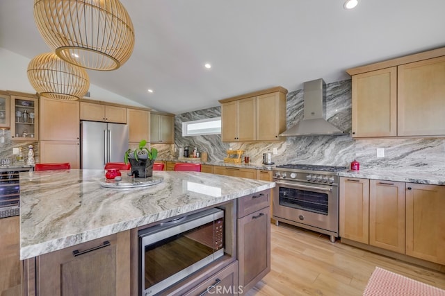 9171 Heatherton Cir, Huntington Beach, CA 92646 - kitchen with high end appliances, wall chimney range hood, vaulted ceiling, light brown cabinetry, and tasteful backsplash