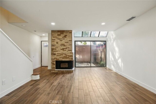 25761 Le Parc Unit 89, Lake Forest, CA 92630 - unfurnished living room featuring wood finished floors, baseboards, a stone fireplace, and recessed lighting