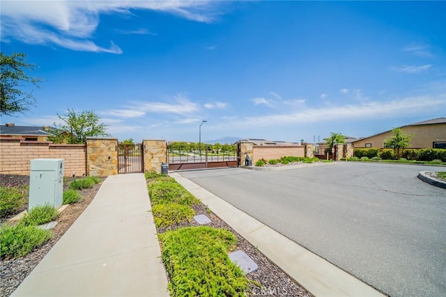 1521 Summerfield Way, Beaumont, CA 92223 - view of asphalt road with a gate, sidewalks, curbs, street lighting, and a gated entry