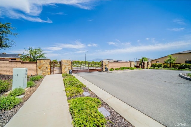 1521 Summerfield Way, Beaumont, CA 92223 - view of asphalt street featuring a gate, sidewalks, curbs, street lighting, and a gated entry