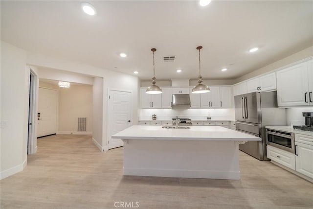 1521 Summerfield Way, Beaumont, CA 92223 - kitchen with appliances with stainless steel finishes, light countertops, white cabinets, an island with sink, and light wood finished floors