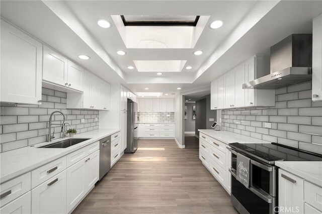1995 Molino Ave Unit 301, Signal Hill, CA 90755 - kitchen with stainless steel appliances, wall chimney exhaust hood, a sink, a raised ceiling, and white cabinets