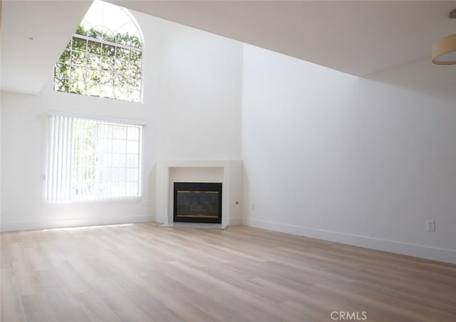 14678 Tupper St, Panorama City, CA 91402 - unfurnished living room featuring wood finished floors, a fireplace with flush hearth, baseboards, and a high ceiling