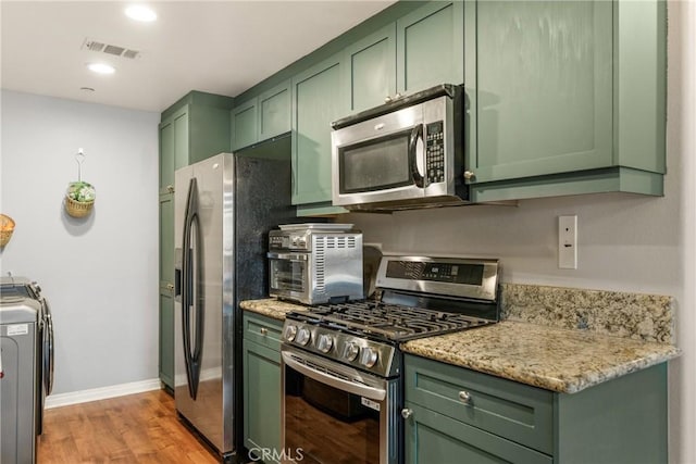 17230 Newhope St Unit 309, Fountain Valley, CA 92708 - kitchen featuring green cabinets, stainless steel appliances, light wood-style floors, baseboards, and light stone countertops