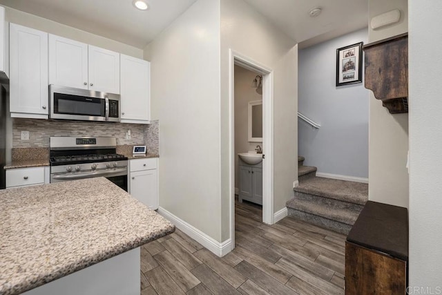 1710 Moon Orchid Ave, Chula Vista, CA 91913 - kitchen featuring stainless steel appliances, baseboards, white cabinetry, a sink, and decorative backsplash