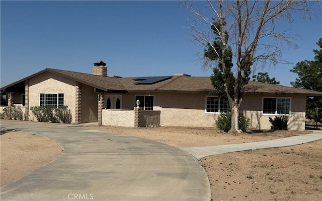 15615 Apache Rd, Apple Valley, CA 92307 - single story home with stucco siding, a chimney, roof mounted solar panels, and curved driveway