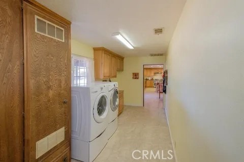 15615 Apache Rd, Apple Valley, CA 92307 - laundry area featuring washing machine and dryer, cabinet space, and light colored carpet