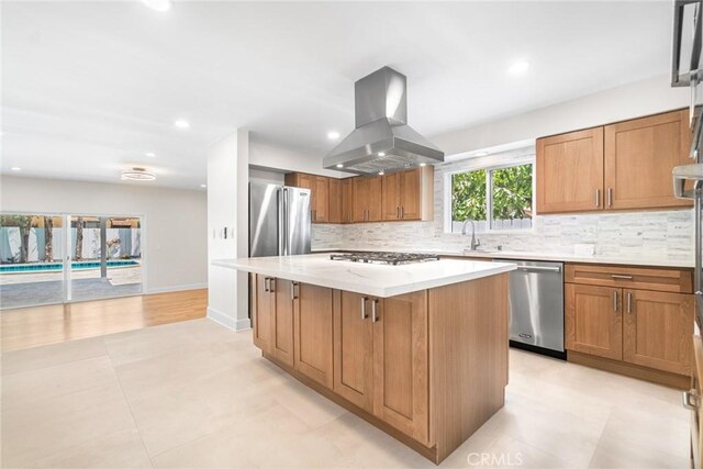 18311 Chase St, Northridge, CA 91325 - kitchen featuring appliances with stainless steel finishes, island range hood, a kitchen island, decorative backsplash, and light stone counters