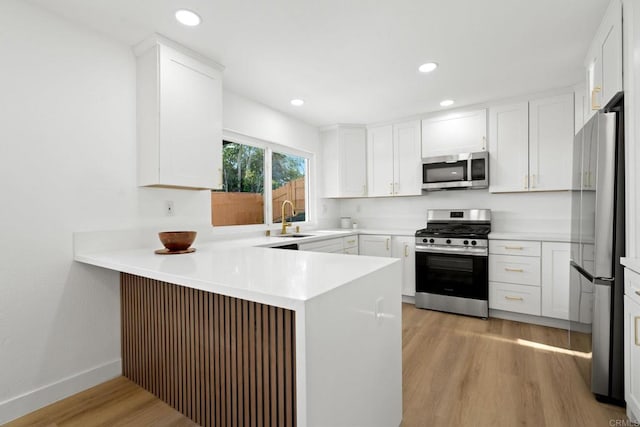 2858 Lehigh Ct, Oceanside, CA 92056 - kitchen featuring stainless steel appliances, a sink, a peninsula, light wood-type flooring, and white cabinets