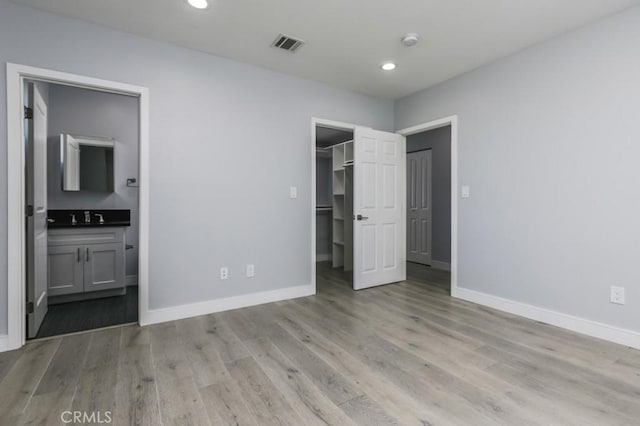 529 W 80th St, Los Angeles, CA 90044 - unfurnished bedroom with baseboards, light wood-type flooring, a spacious closet, recessed lighting, and ensuite bath