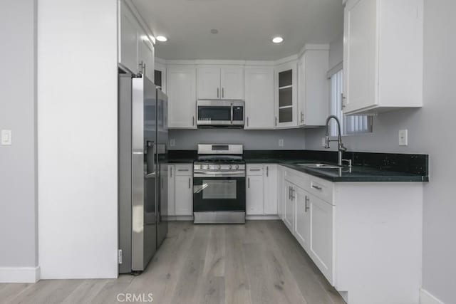 529 W 80th St, Los Angeles, CA 90044 - kitchen featuring stainless steel appliances, a sink, light wood-style floors, dark countertops, and white cabinetry