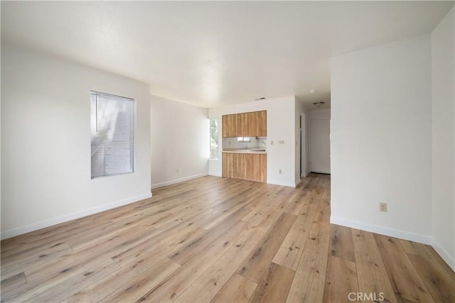 2975 Rockview Pl # 2, San Luis Obispo, CA 93401 - unfurnished living room featuring light wood-type flooring, baseboards, and a sink
