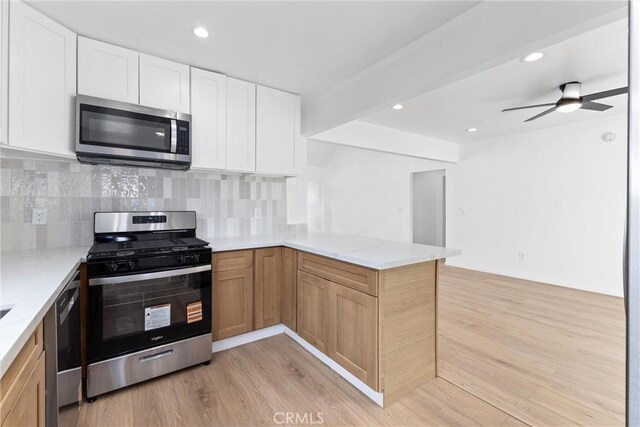 15447 Romar St, Mission Hills San Fernando, CA 91345 - kitchen featuring stainless steel appliances, a peninsula, light wood-style floors, light stone countertops, and backsplash