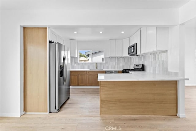 15447 Romar St, Mission Hills San Fernando, CA 91345 - kitchen with stainless steel appliances, a peninsula, a sink, light countertops, and light wood finished floors