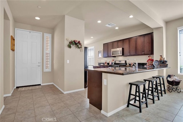 11156 Camden St, Apple Valley, CA 92308 - kitchen with appliances with stainless steel finishes, a kitchen bar, dark brown cabinets, a peninsula, and baseboards
