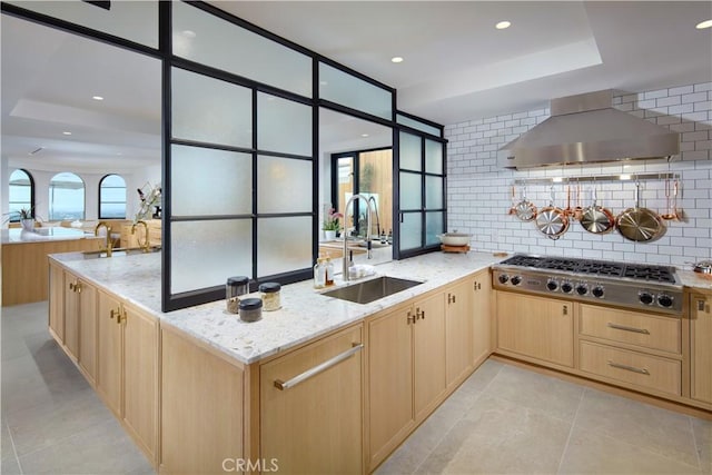 17 Muir Beach Cir, Corona Del Mar, CA 92625 - kitchen featuring wall chimney range hood, light brown cabinetry, stainless steel gas stovetop, a sink, and a tray ceiling