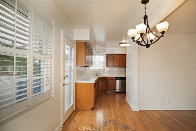 7228 Bairnsdale St, Downey, CA 90240 - kitchen with dishwasher, tile counters, brown cabinetry, light wood-style floors, and backsplash