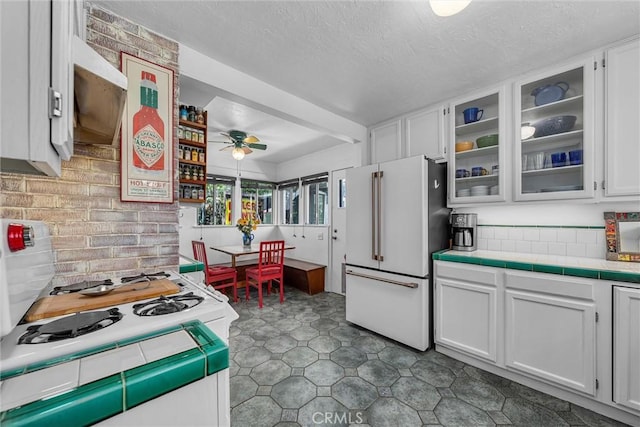 4039 W 7th St, Los Angeles, CA 90005 - kitchen featuring freestanding refrigerator, a ceiling fan, tile countertops, white cabinetry, and glass insert cabinets