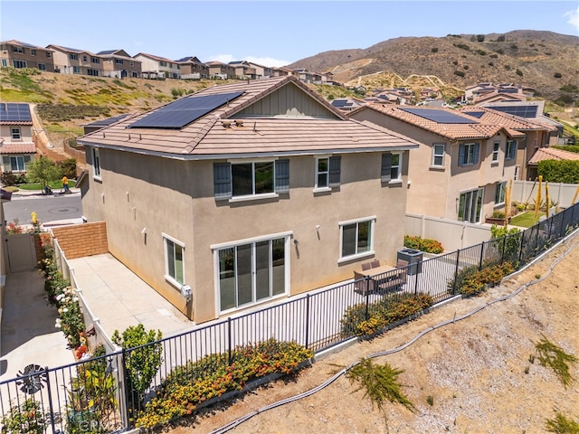 11757 Stonefield Dr, Corona, CA 92883 - rear view of property featuring stucco siding, roof mounted solar panels, a fenced backyard, and a mountain view
