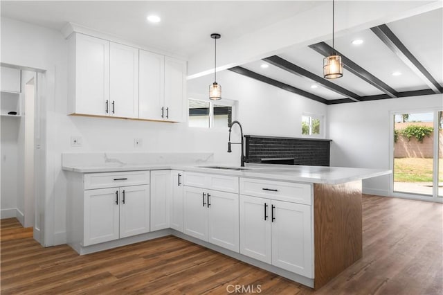 424 E Victoria St, Rialto, CA 92376 - kitchen featuring a sink, a peninsula, beamed ceiling, dark wood-type flooring, and white cabinetry