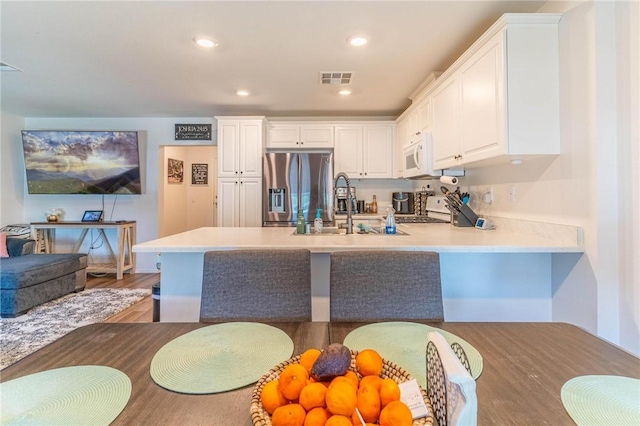 7155 Citrus Ave Unit 367, Fontana, CA 92336 - kitchen featuring stainless steel fridge, white microwave, a peninsula, white cabinetry, and a sink
