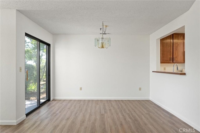 9 Coolwater, Chico, CA 95928 - unfurnished dining area featuring light wood-style floors, a textured ceiling, a sink, baseboards, and a chandelier