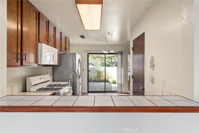 9 Coolwater, Chico, CA 95928 - kitchen featuring white appliances, tile counters, brown cabinets, and a peninsula