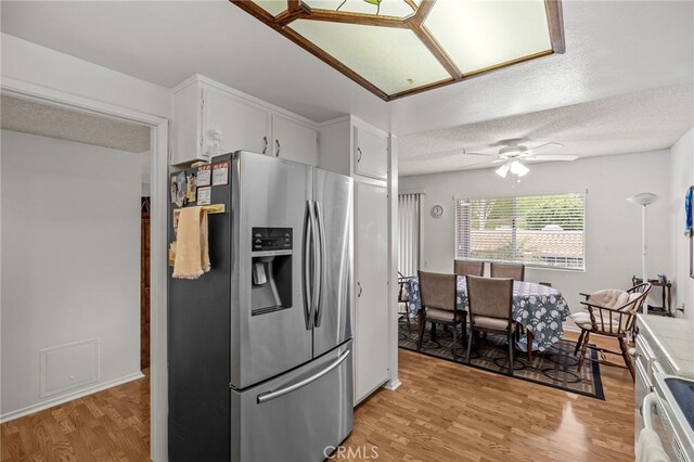 5359 Algarrobo Unit 1A, Laguna Woods, CA 92637 - kitchen featuring stainless steel refrigerator with ice dispenser, light wood finished floors, a ceiling fan, white cabinetry, and a textured ceiling