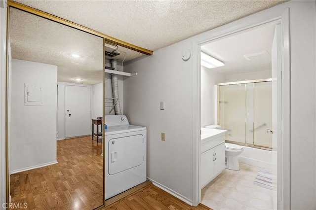 5359 Algarrobo Unit 1A, Laguna Woods, CA 92637 - washroom with washer / dryer, light wood-type flooring, a textured ceiling, and baseboards