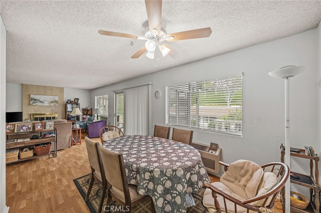 5359 Algarrobo Unit 1A, Laguna Woods, CA 92637 - dining room with a textured ceiling, light wood-style flooring, a ceiling fan, and a fireplace