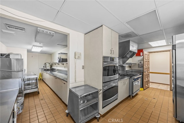 5359 Algarrobo Unit 1A, Laguna Woods, CA 92637 - kitchen featuring appliances with stainless steel finishes, light tile patterned floors, stainless steel countertops, a drop ceiling, and white cabinetry
