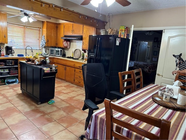 4535 Ramsdell Ave, La Crescenta, CA 91214 - kitchen featuring a ceiling fan, under cabinet range hood, black fridge, brown cabinetry, and a textured ceiling