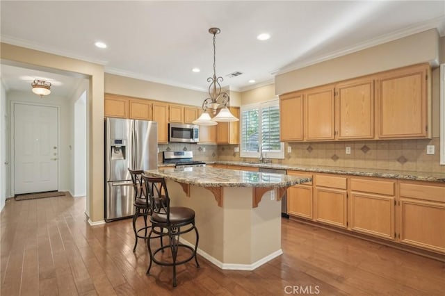 28523 Santa Catarina Rd, Saugus, CA 91350 - kitchen with appliances with stainless steel finishes, a kitchen breakfast bar, hardwood / wood-style floors, light stone countertops, and a kitchen island