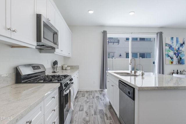 1607 Dundas Pl, Upland, CA 91784 - kitchen featuring appliances with stainless steel finishes, a sink, white cabinetry, light wood finished floors, and a center island with sink
