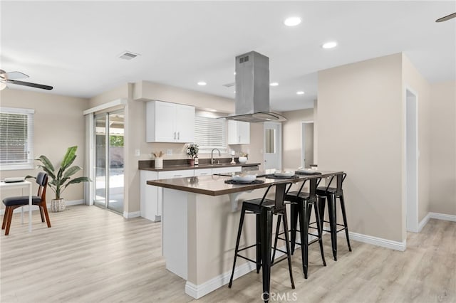 26331 Foxgrove Rd, Menifee, CA 92586 - kitchen featuring island range hood, dark countertops, ceiling fan, a sink, and a kitchen bar