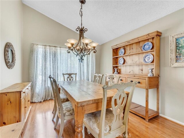 23403 Via Castanet, Valencia, CA 91355 - dining area featuring vaulted ceiling, a chandelier, light wood finished floors, a textured ceiling, and baseboards