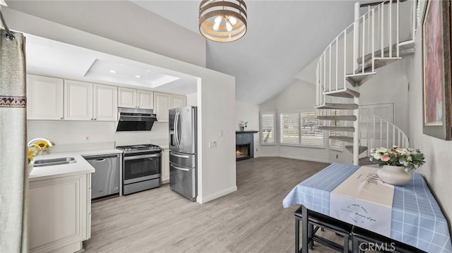 10133 Shinon Dr, Rancho Cucamonga, CA 91737 - kitchen featuring stainless steel appliances, a sink, light wood-style floors, light countertops, and a warm lit fireplace