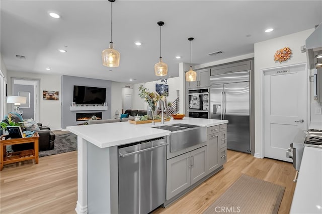 2760 Chad Zeller Ln, Corona, CA 92882 - kitchen with stainless steel appliances, gray cabinets, light wood-style flooring, open floor plan, and recessed lighting