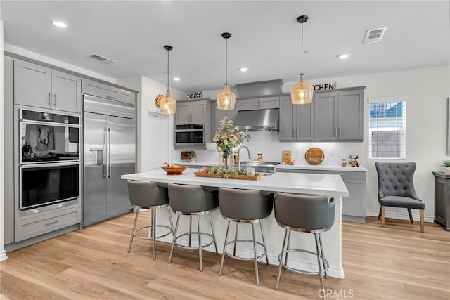 2760 Chad Zeller Ln, Corona, CA 92882 - kitchen featuring built in fridge, gray cabinetry, under cabinet range hood, double oven, and light countertops